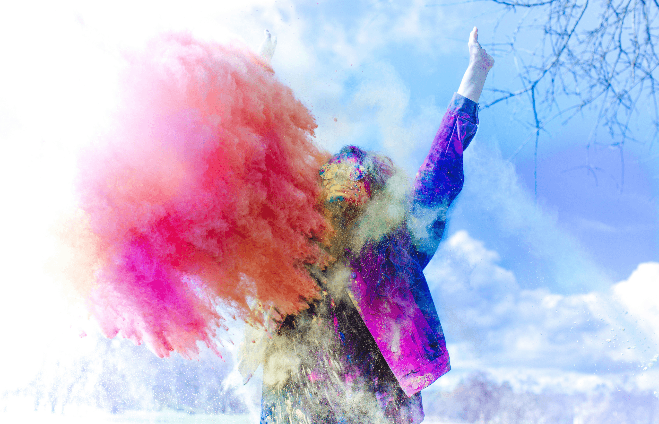 Woman with hands in the air and color powder thrown at her illustrating what will happen at Paint the Prairie color fun run at Painted Prairie